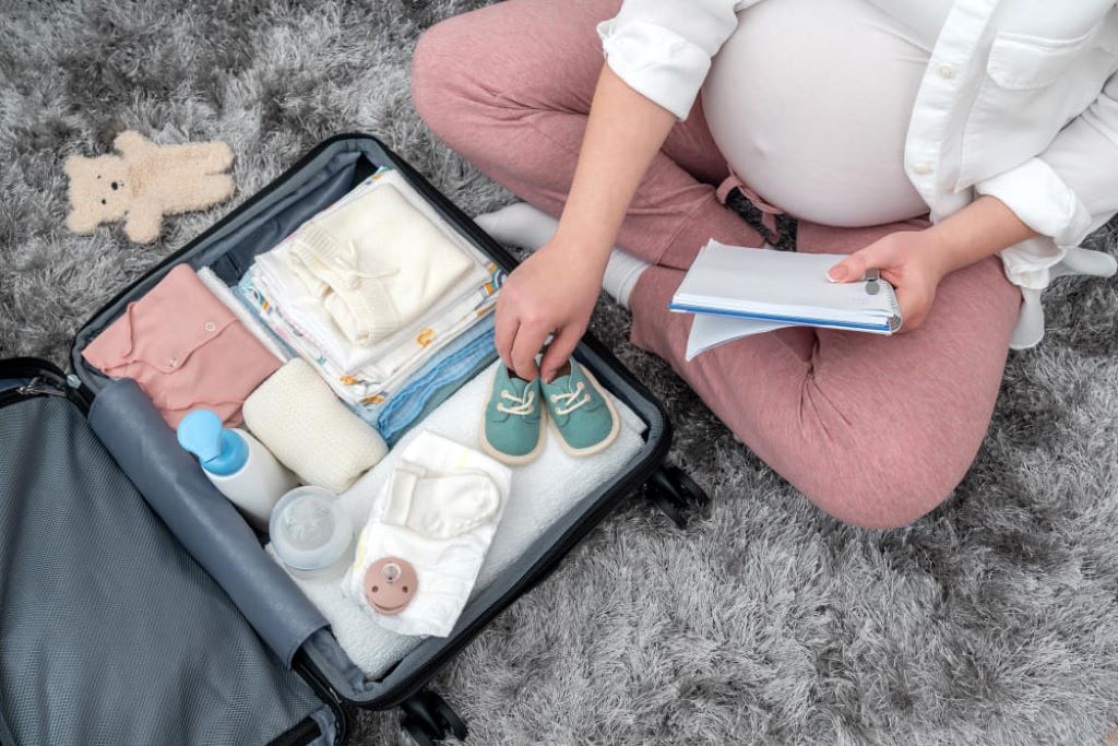 Parent packing essential baby travel accessories in a diaper bag