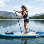 Inflatable stand up paddle board resting on a sunny sandy beach.