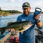 Angler weighing a large bass with a digital fish scale on a Texas lake.