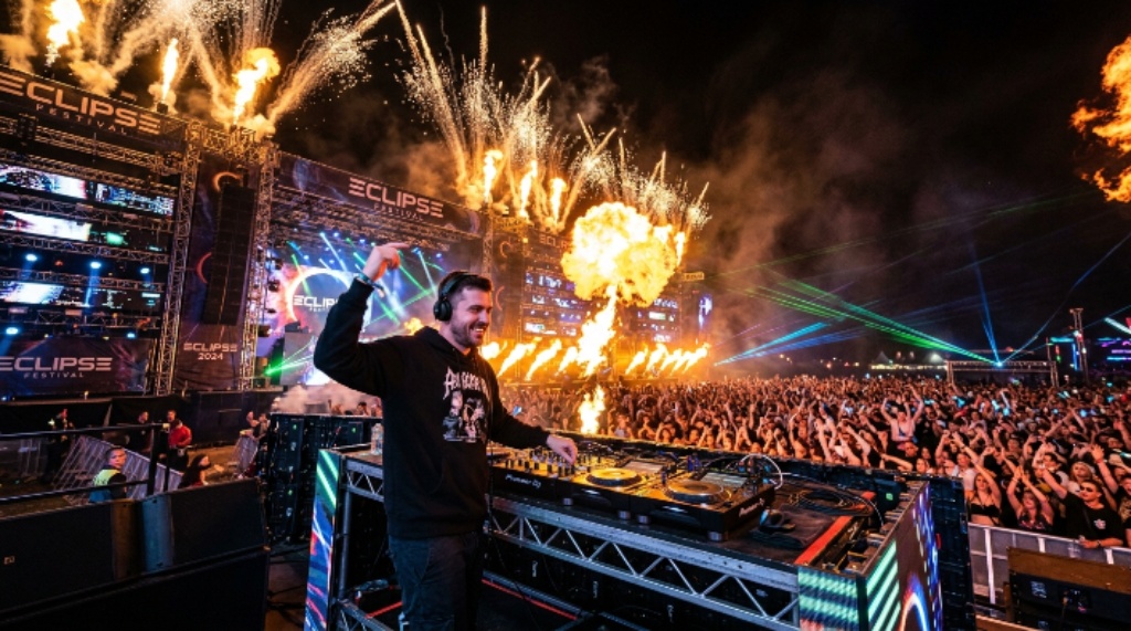 DJ performing on a large festival stage with pyrotechnics