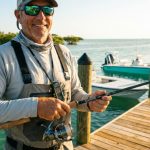 Angler holding a spinning fishing rod combo on a sunny Florida dock.